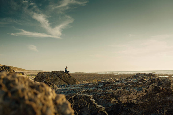 Beutoful kobieta sama na plaży siedzi na skałach - Zdjęcie, obraz