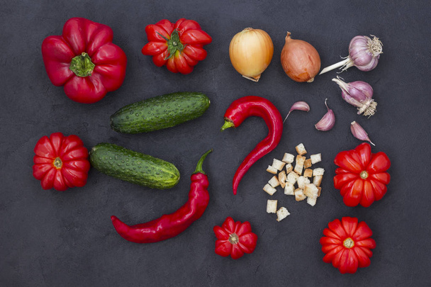 Set of vegetables on a black background: tomatoes, cucumbers, peppers, garlic and onion - Photo, image