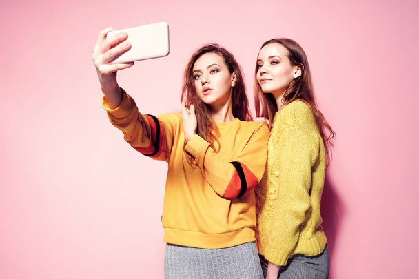 Two cheerful young women talking selfie over pink background - Photo, image