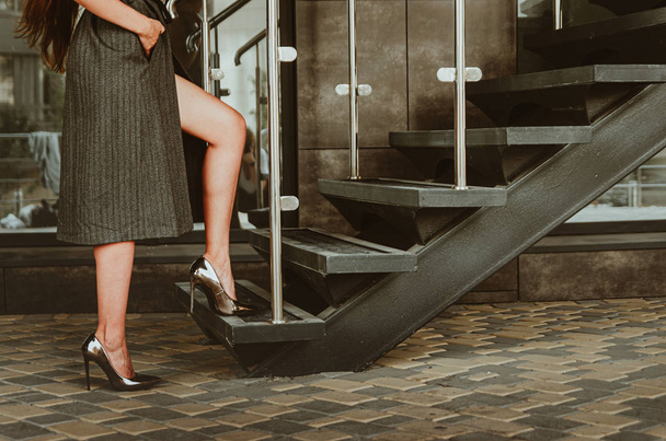 Piękne kobiece nogi w metalowych wysokogazowych butach wspiąć się na schodach - Zdjęcie, obraz