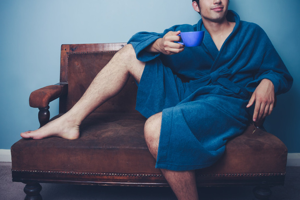 Man relaxing on vintage sofa with cup of coffee - Foto, imagen