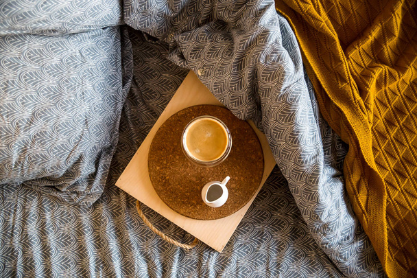 Musta kahvi läpinäkyvässä kupissa sängyssä syksyllä aamulla
 - Valokuva, kuva