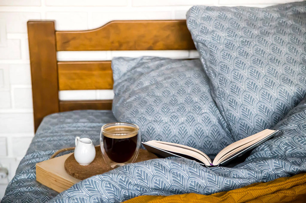 Czarna kawa w przezroczystym kubku w łóżku jesienią rano - Zdjęcie, obraz