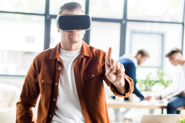 young businessman touching something with finger while using virtual reality headset in office - Фото, зображення