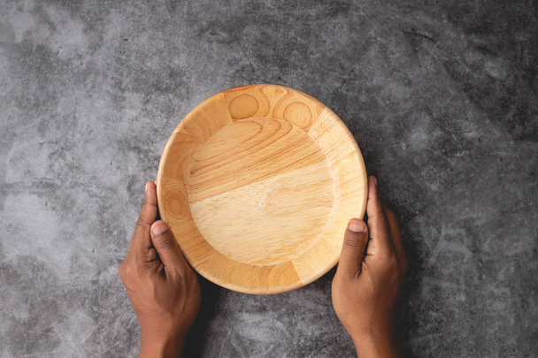 mano umana tenere piatto di legno vuoto su cemento parete texture backgr
 - Foto, immagini