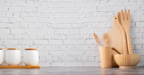 ξύλινα μαγειρικά σκεύη και κύπελλα σε λευκό τούβλο υφή τοίχο προγρού - Φωτογραφία, εικόνα
