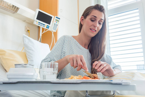 Pacjent w szpitalu leżącego w łóżku jedzenia posiłku - Zdjęcie, obraz