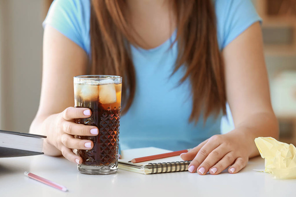 Woman with glass of cold cola sitting at table in office - Photo, Image