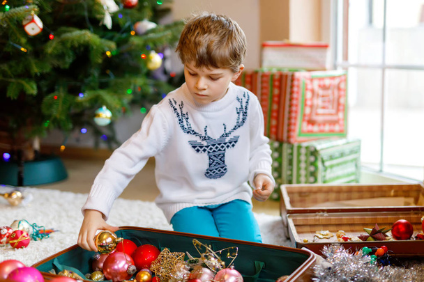 Schöner Junge und bunte Vintage-Weihnachtsspielzeuge und -Bälle. Kind schmückt Weihnachtsbaum - Foto, Bild