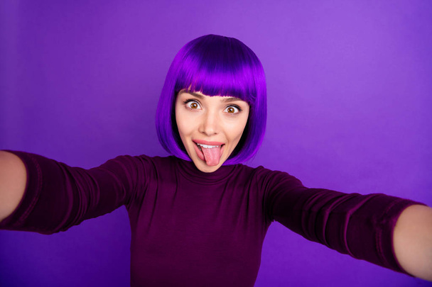 Pretty lady making self photos sticking tongue out mouth wear trendy clothes and wig isolated purple background - Φωτογραφία, εικόνα