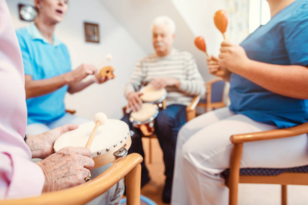 Senioren in verpleeghuis muziek maken met ritme-instrumenten - Foto, afbeelding