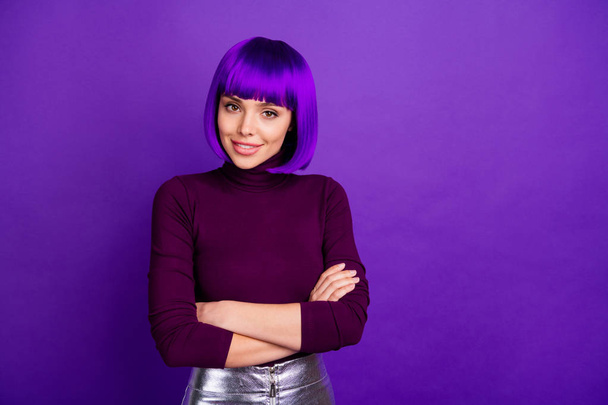 Portrait of pretty woman with her arms crossed looking smiling wearing turtleneck isolated over purple violet background - Photo, image