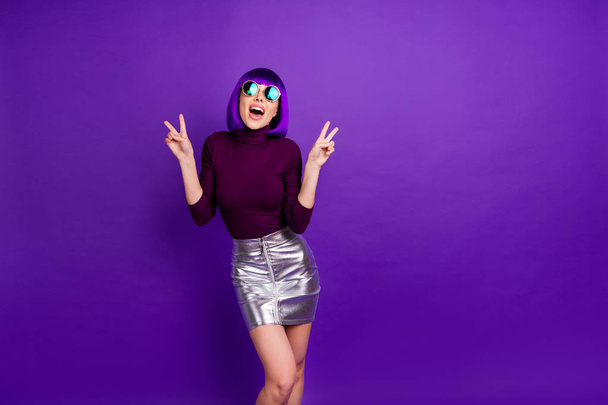 Portrait of charming millennial with eyeglasses eyewear making v-signs wearing turtleneck isolated over purple violet background - Foto, Imagem