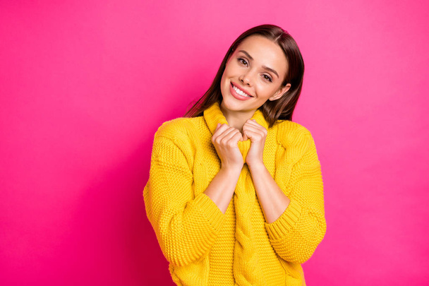 Portrait of charming lady looking with beaming smile touching her collar wearing knitted jumper isolated over pink bright background - Foto, imagen