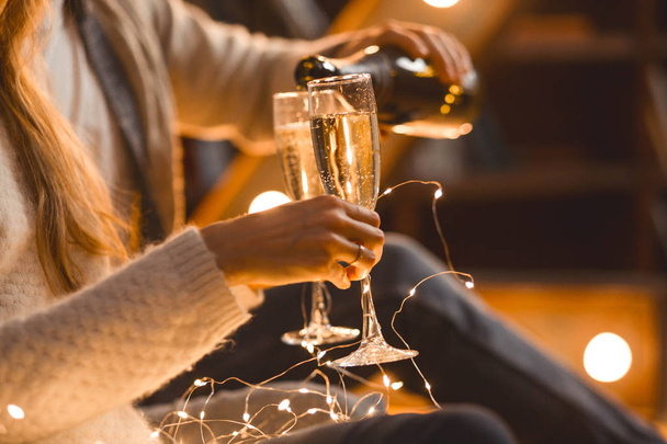 férfi és nő iszik pezsgőt egy hangulatos szobában az esti környezetben - Fotó, kép