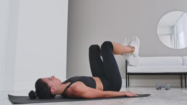 Сила тренировки веса тела тренировки женщина-спортсмен делает Flutter Kicks. Европейская взрослая женщина делает упражнения на полу с ногой Поднимает для тренировки мышц пресса дома в его квартире
. - Кадры, видео