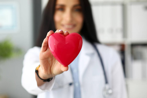 Женский кардиолог держит в руках красное сердце игрушки
 - Фото, изображение