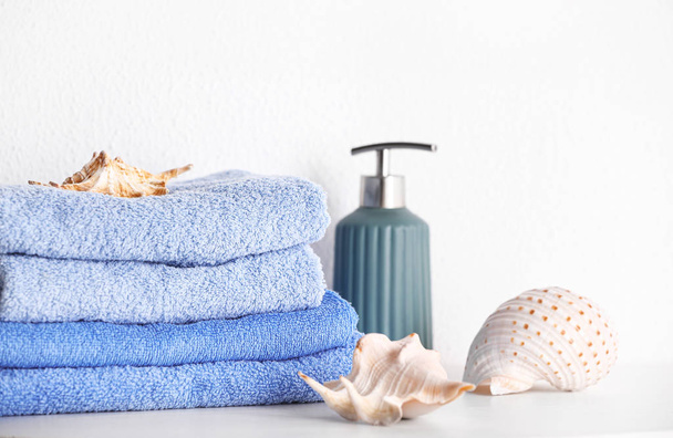 Στοίβα από καθαρές πετσέτες με σαπούνι και κοχύλια στο τραπέζι - Φωτογραφία, εικόνα