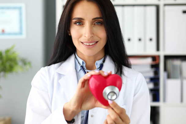 Mãos de mulher GP segurando cabeça estetoscópio perto de coração de brinquedo vermelho
 - Foto, Imagem