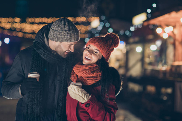 Photo of two people with hot beverage in hands spending x-mas evening outdoors telling humorous jokes having best time wearing warm jackets - Φωτογραφία, εικόνα