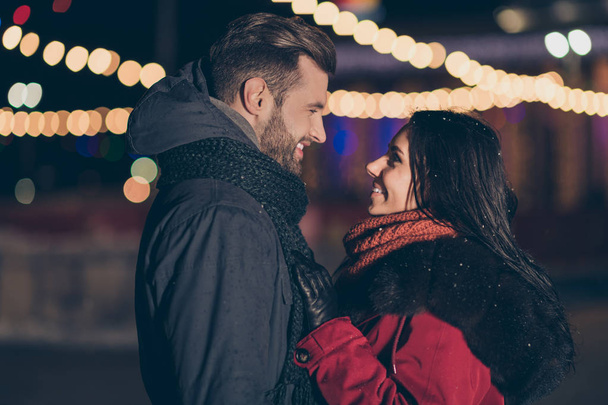 Foto de dos novios enamorados que asisten al parque de la ciudad a la medianoche de año nuevo de pie enfrente con abrigadas chaquetas de invierno al aire libre
 - Foto, imagen