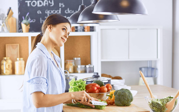 若い女性は、台所で食べ物を準備します。健康食品 - 野菜 - 写真・画像