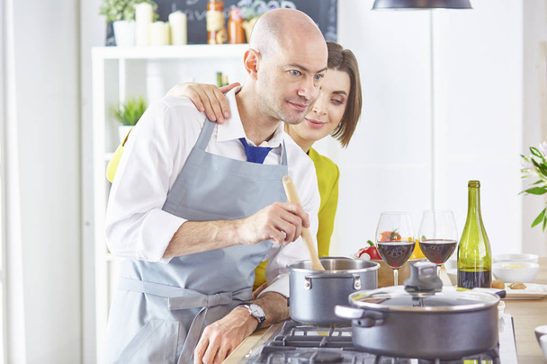 Uśmiechnięta młoda para gotuje jedzenie w kuchni - Zdjęcie, obraz