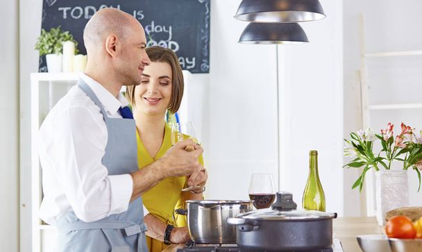 Sonriente pareja joven cocinando comida en la cocina - Foto, Imagen