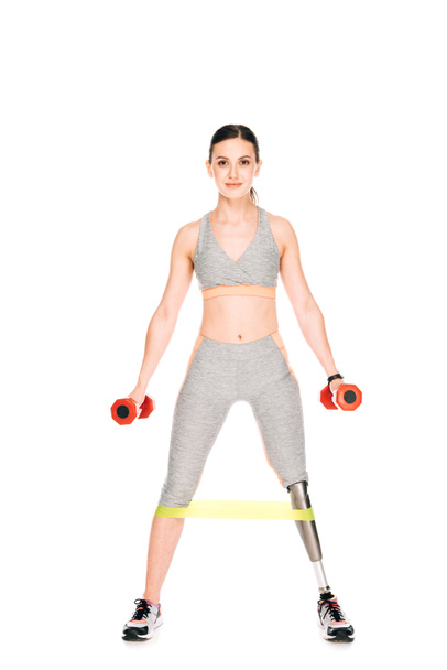 full length view of disabled sportswoman with resistance band and dumbbells isolated on white - Fotó, kép