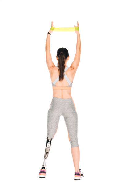 back view of disabled sportswoman with prosthesis training with resistance band isolated on white - 写真・画像
