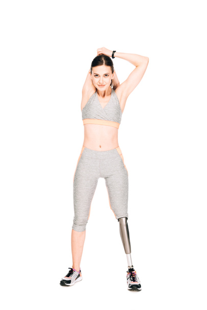full length view of disabled sportswoman with prosthesis stretching isolated on white - Zdjęcie, obraz