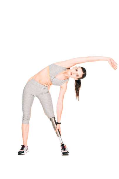 full length view of disabled sportswoman with prosthesis stretching isolated on white - Foto, afbeelding