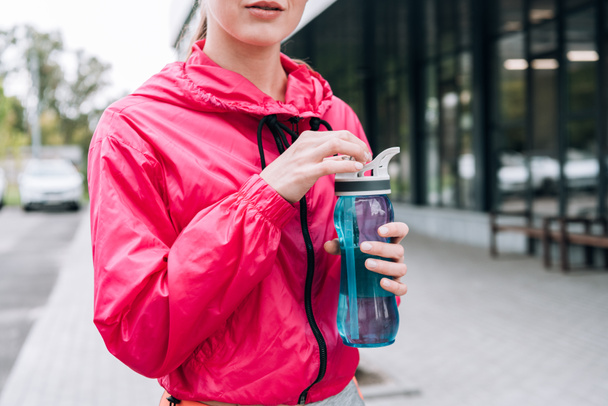 partial view of sportswoman holding sport bottle on street - Photo, image