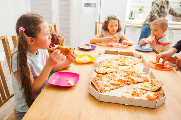 Children eating pizza, the home birthday party - Фото, изображение