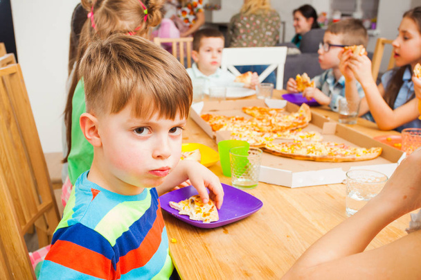 Children eating pizza on the kids meeting - 写真・画像