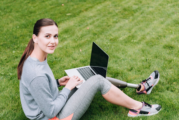 Behinderte Sportlerin benutzt Laptop mit leerem Bildschirm im Gras - Foto, Bild