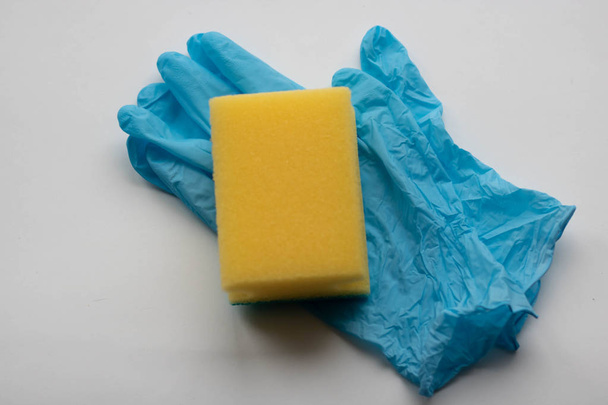 Guantes de goma y esponja de cocina sobre fondo claro. Esponja de lavado y guantes protectores. Limpieza
 - Foto, imagen