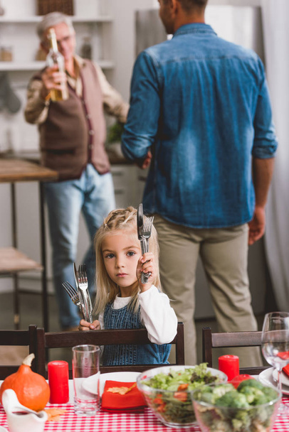 selective focus of cute kid smiling and holding cutlery in Thanksgiving day   - Photo, Image