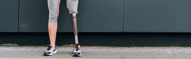 panoramic shot of disabled sportswoman with prosthetic leg on street - Foto, immagini