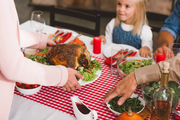 cropped view of mother holding plate with turkey in Thanksgiving day    - 写真・画像