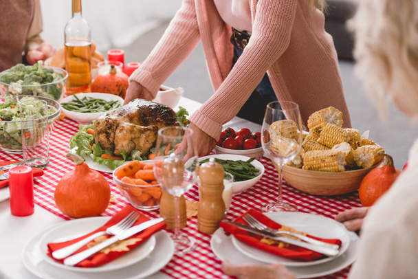 bijgesneden weergave van moeder zetten op tafel plaat met kalkoen in Thanksgiving dag    - Foto, afbeelding