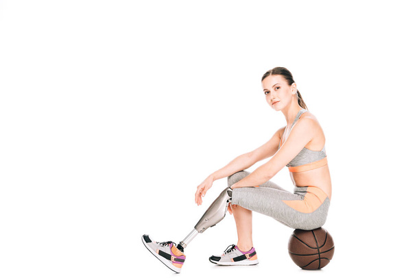 disabled sportswoman sitting on basketball ball isolated on white - Fotografie, Obrázek