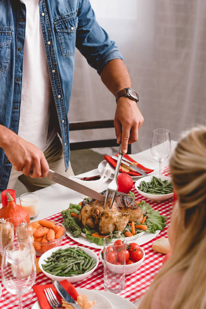 visão cortada de membros da família sentados à mesa e pai cortando peru saboroso no dia de Ação de Graças
       - Foto, Imagem