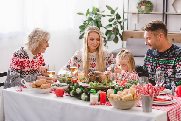 smiling family members sitting at table and celebrating Christmas  - Foto, imagen