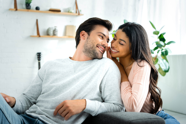 african american woman and handsome man smiling and looking at each other in apartment  - Photo, Image