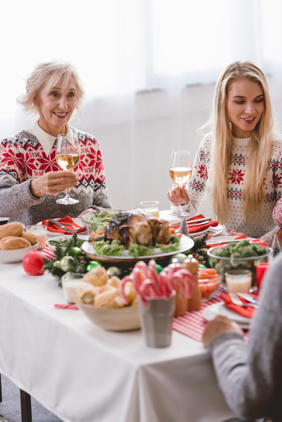family members sitting at table and holding wine glasses in Christmas  - 写真・画像