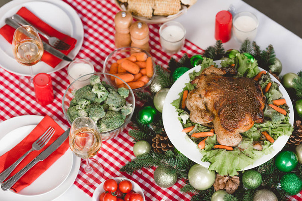 nagy látószögű kilátás zöldségek, pulyka, cseresznye paradicsom, borospohár, gyertyák az asztalon karácsonykor  - Fotó, kép