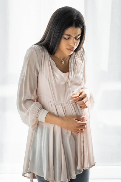 mujer afroamericana embarazada tocando el vientre y sintiendo dolor
  - Foto, Imagen