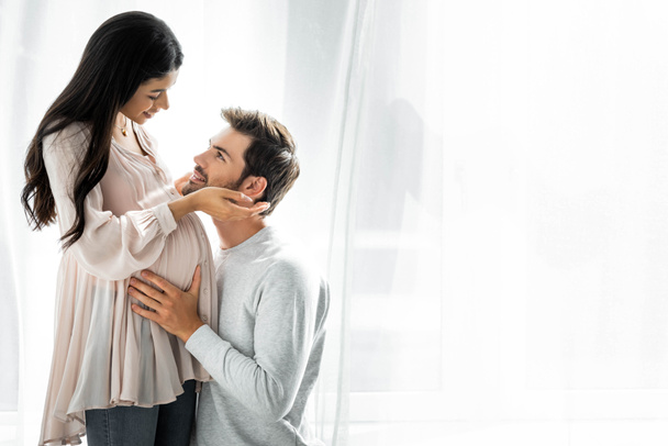 knappe man knuffelen buik van zijn zwangere Afro-Amerikaanse vrouw  - Foto, afbeelding