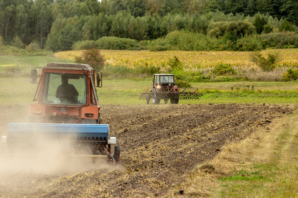 A tractor rips the ground in a dusty field. - Zdjęcie, obraz